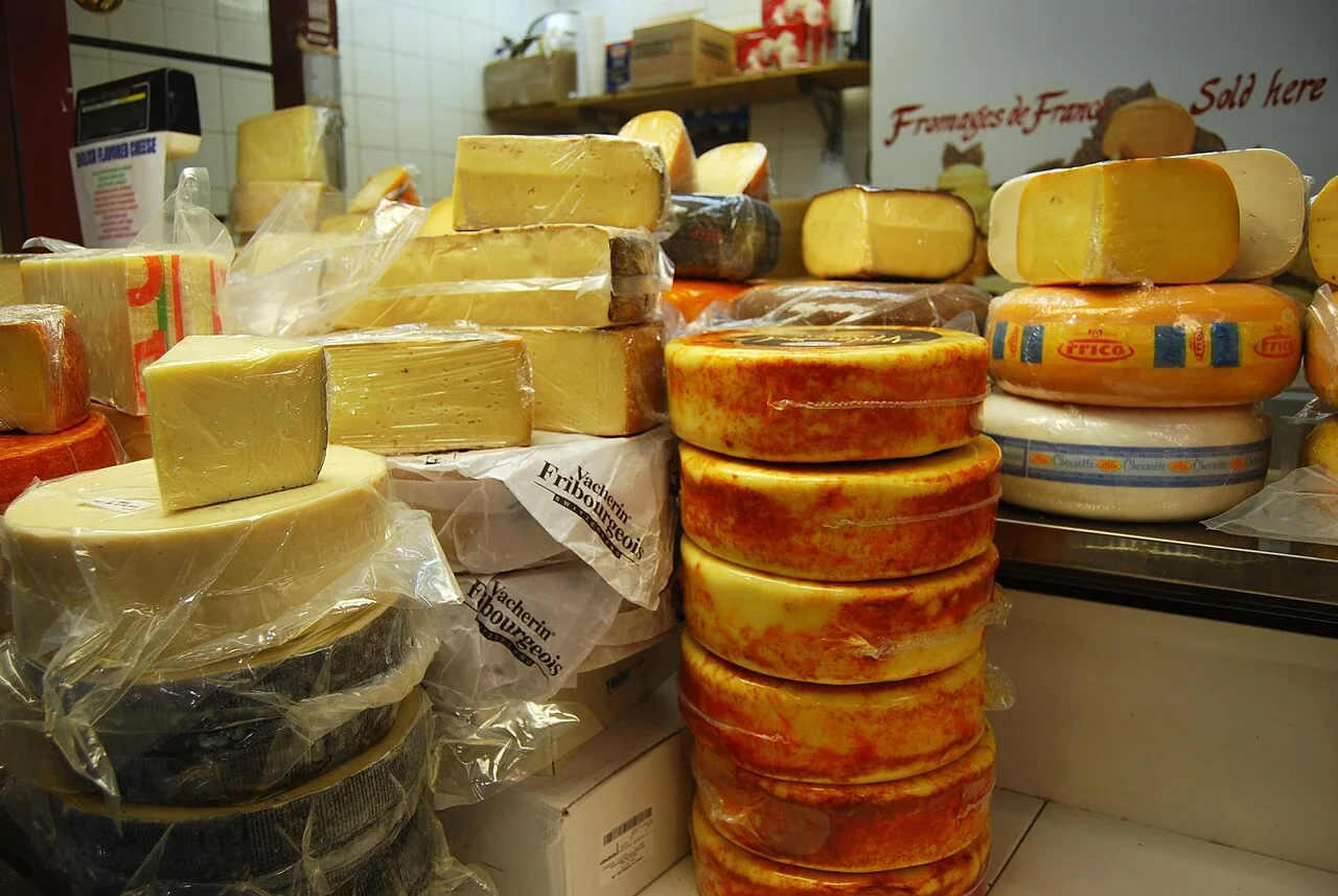 Cheese wheels and blocks fill a shop counter.