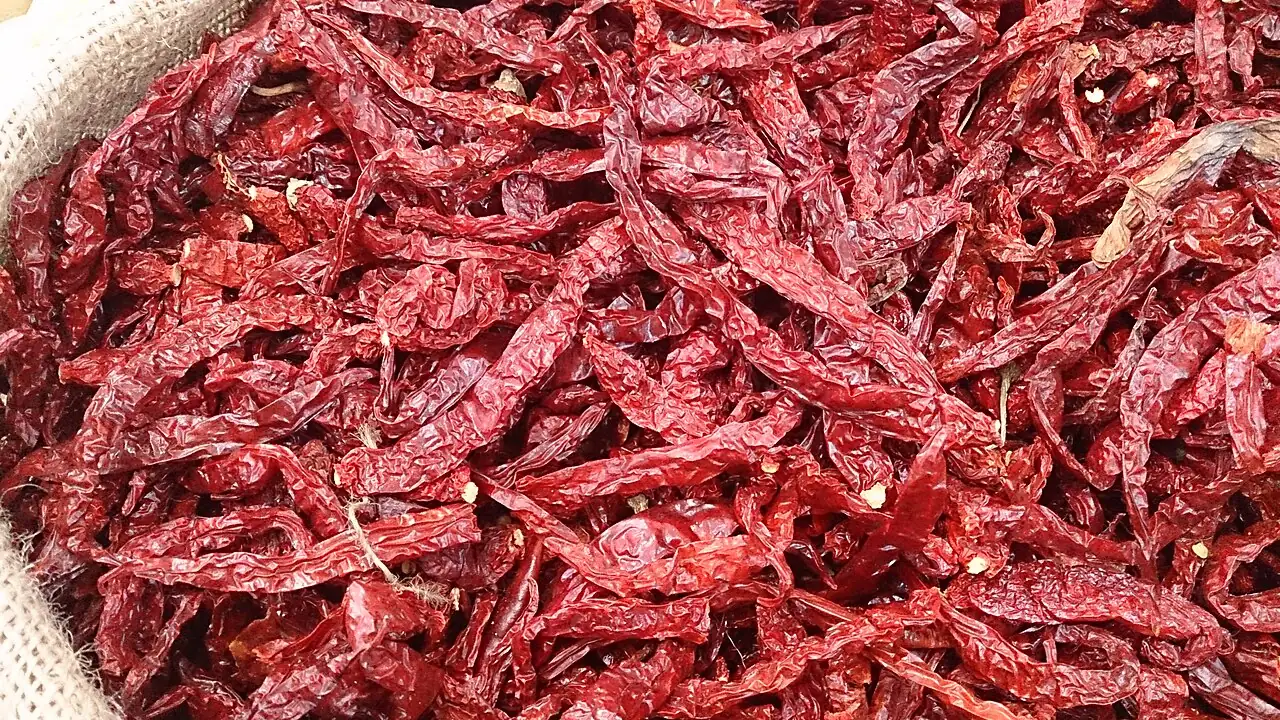A pile of dried red chillies displayed for sale in a basket.