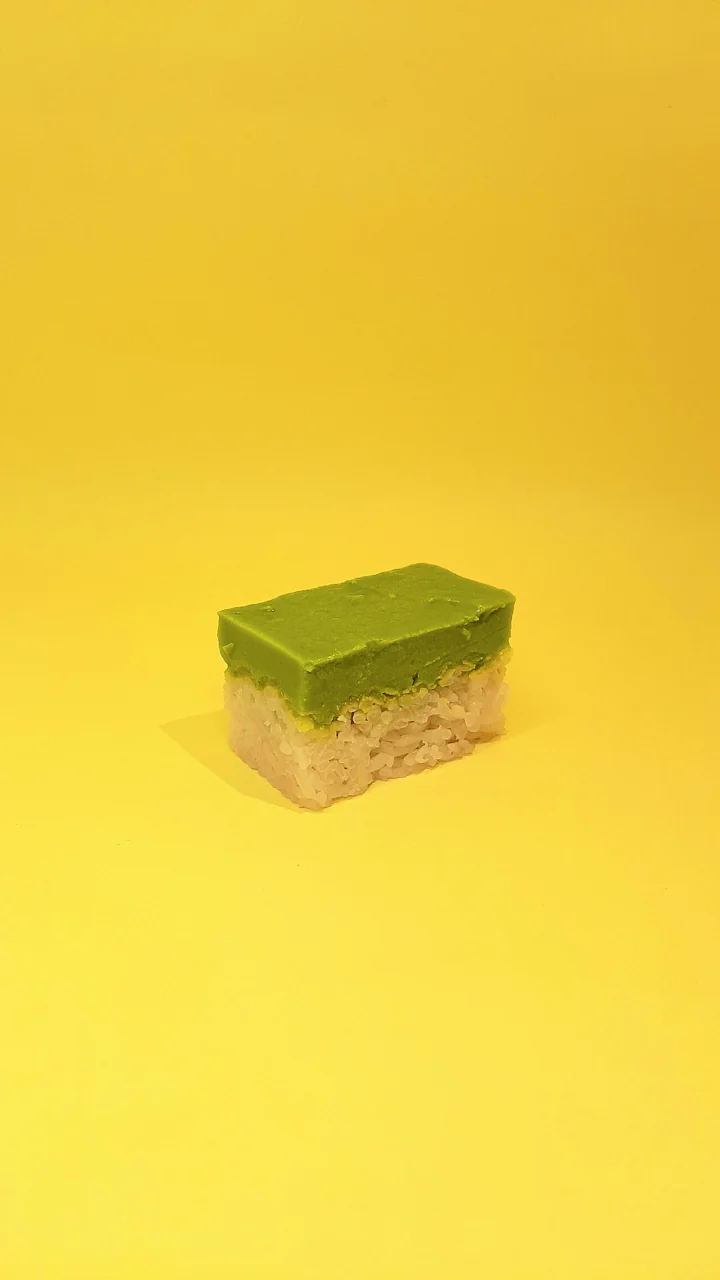 A slice of kueh salat with a green custard layer over white glutinous rice.