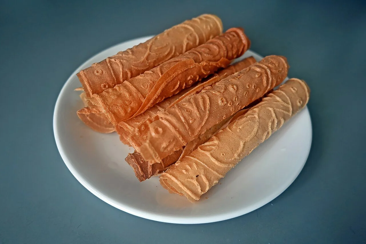 Rolled egg biscuits with patterned surfaces rest on a white plate.