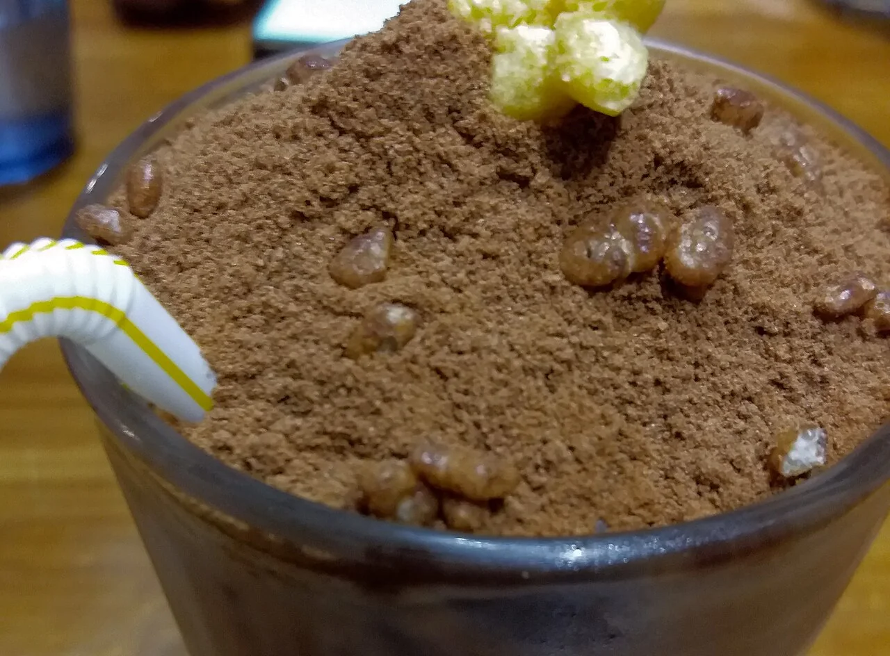 A cup of Milo dinosaur topped with a thick layer of undissolved Milo powder.