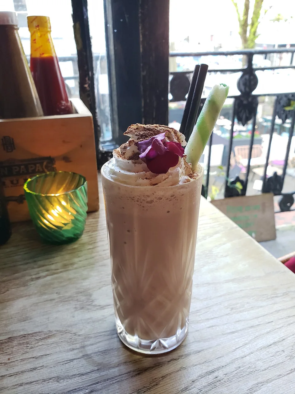 A Milo milkshake topped with cream, cocoa dust, and a flower.