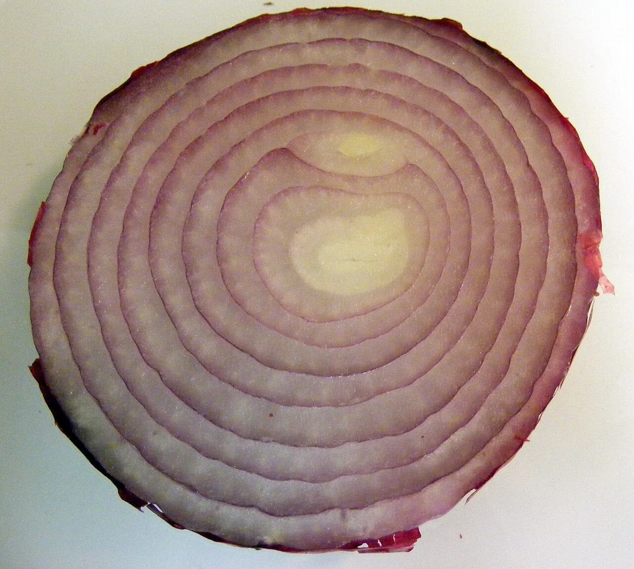 A cut red onion shows concentric purple and white rings.
