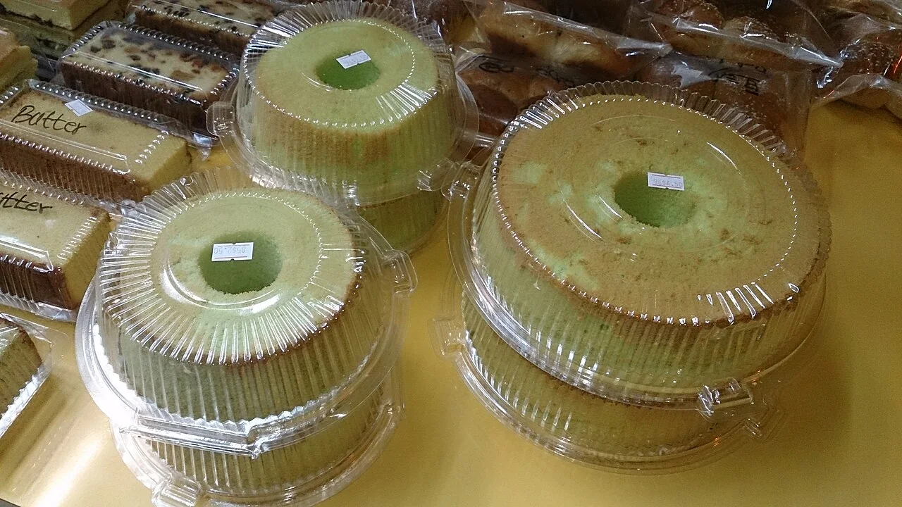 Several green pandan chiffon cakes displayed in clear plastic packaging on a table.