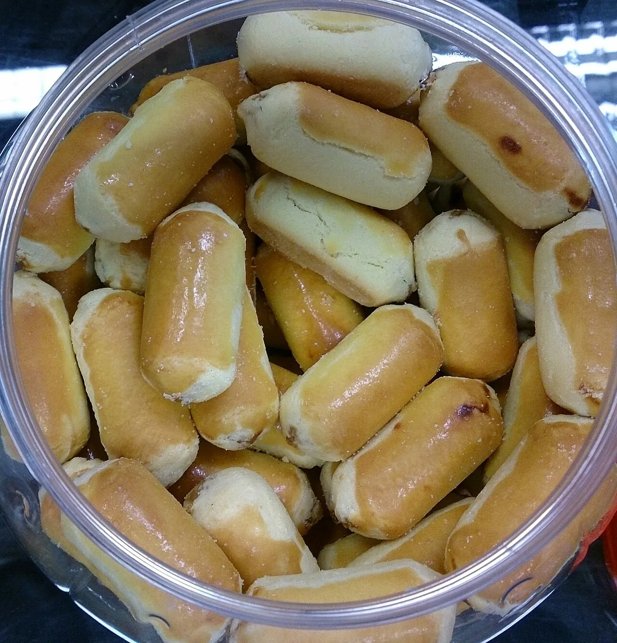 A clear plastic container filled with golden-brown pineapple tarts.