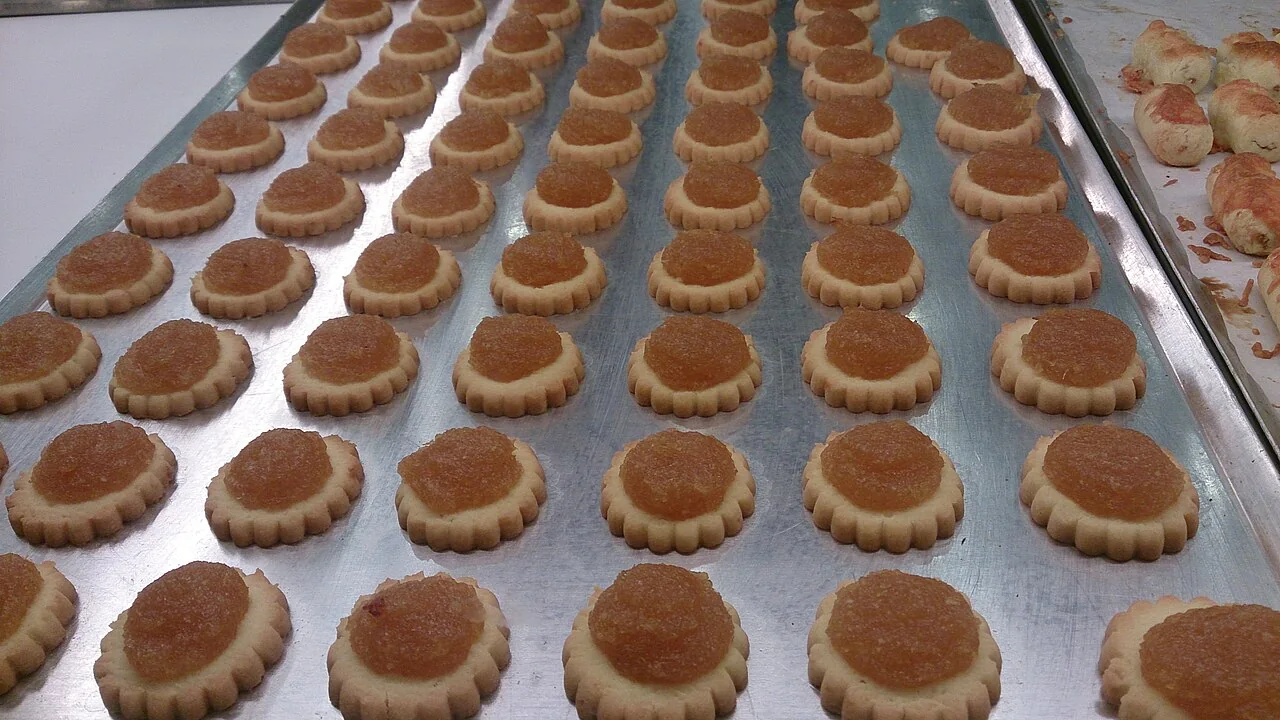 Rows of pineapple tarts arranged on a metal baking tray.