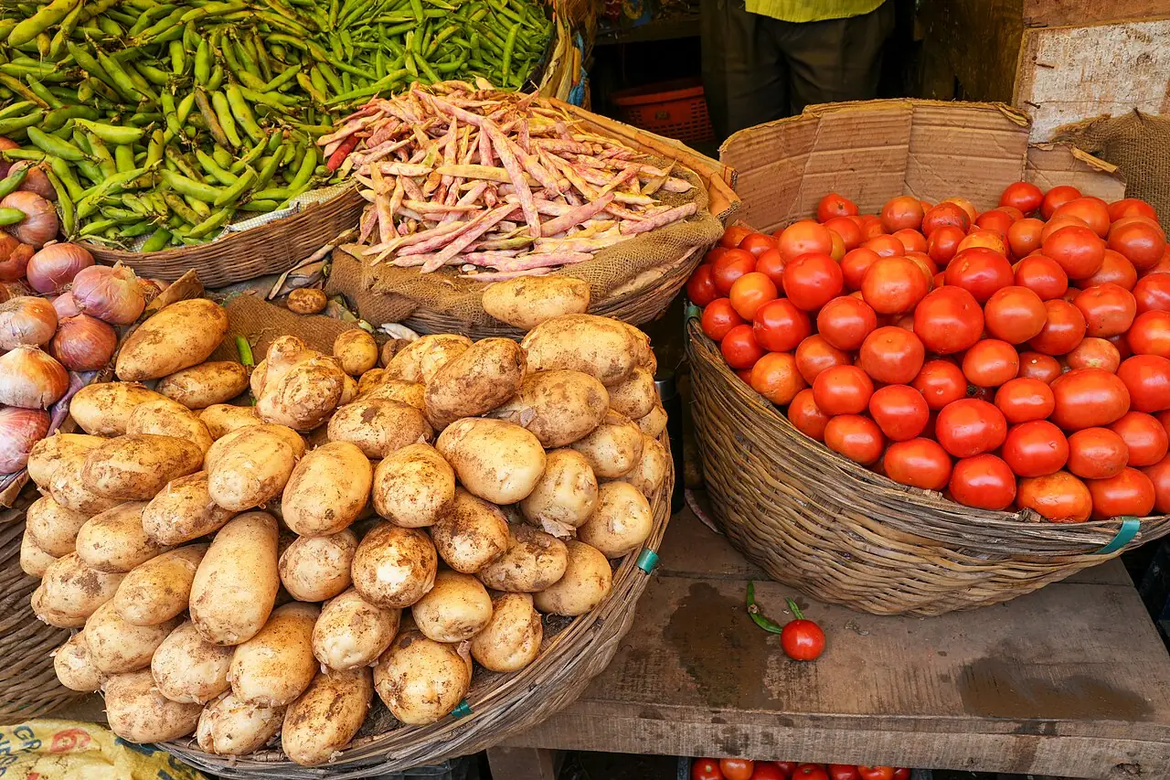 A basket filled with potatoes sits on a wooden table at a market stall.