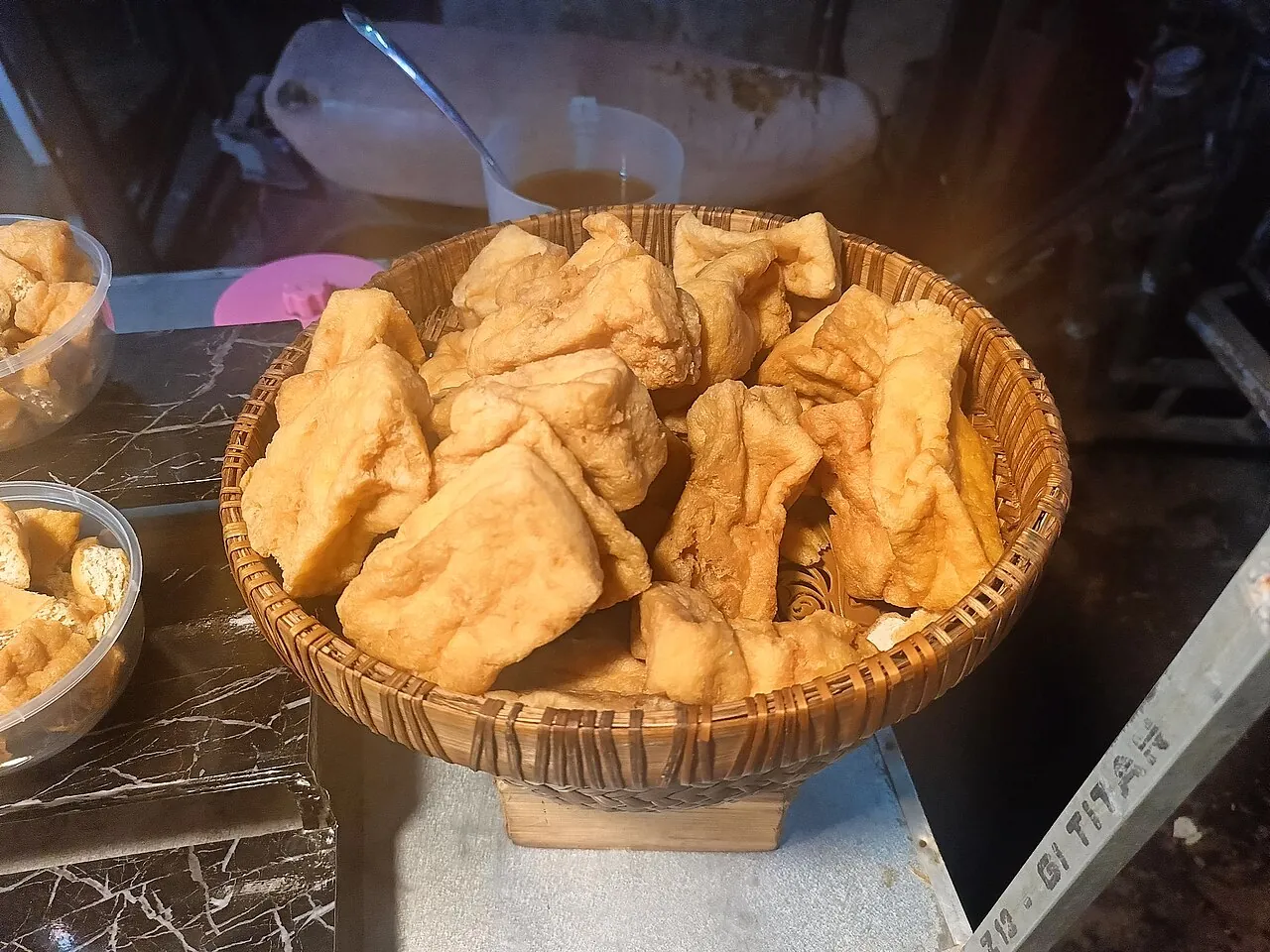 A woven basket is filled with golden pieces of fried tofu.