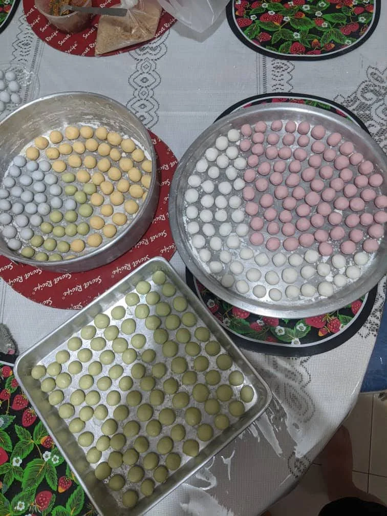Colorful glutinous rice balls are arranged on metal trays.