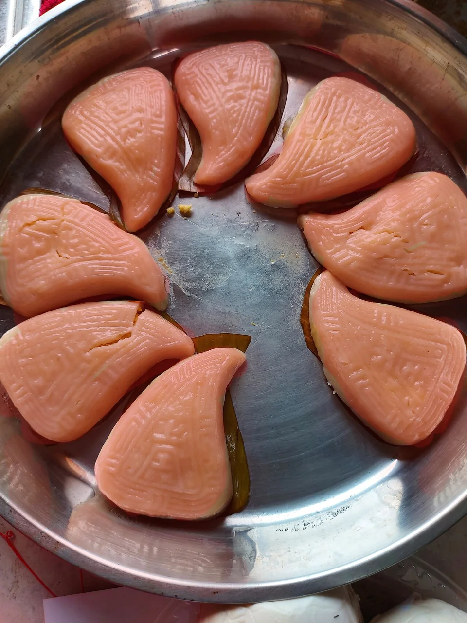 Pink Teochew red-peach cakes sit on a metal tray.