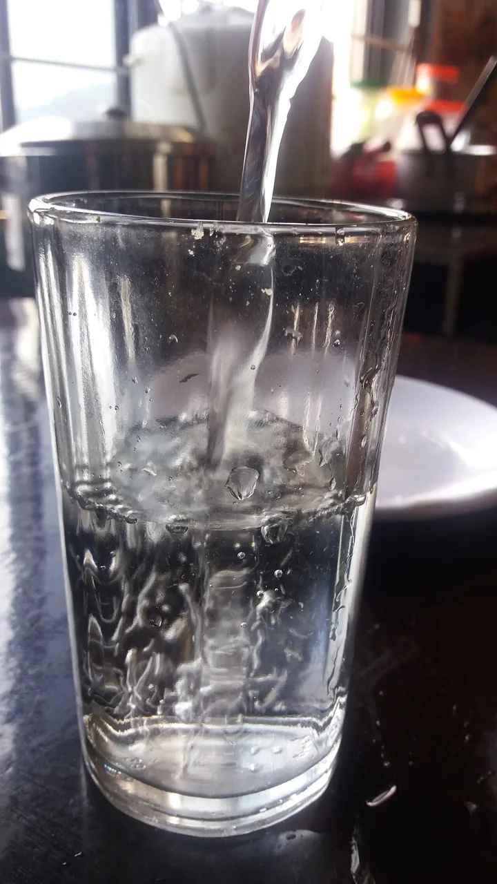 Water is poured into a clear drinking glass.