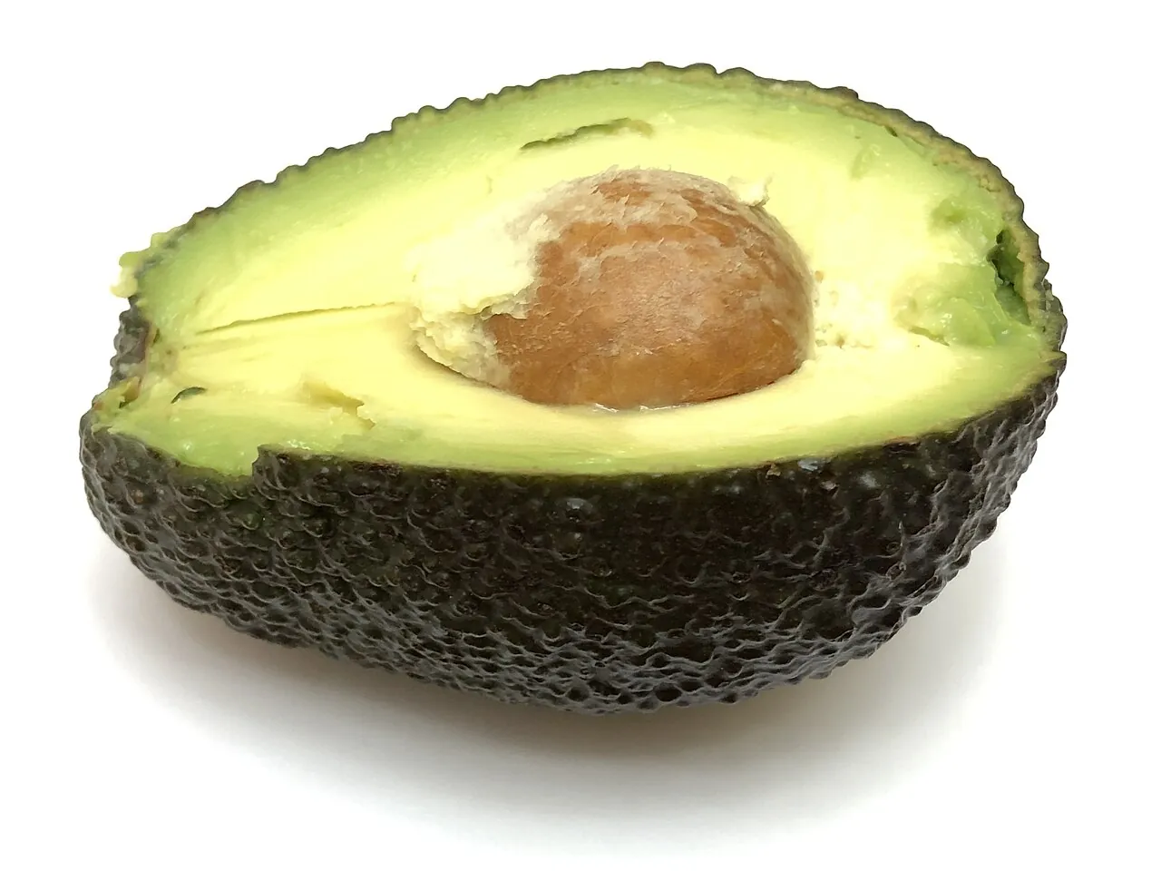 Avocado — Half an avocado, soft and green, with the seed still in it.