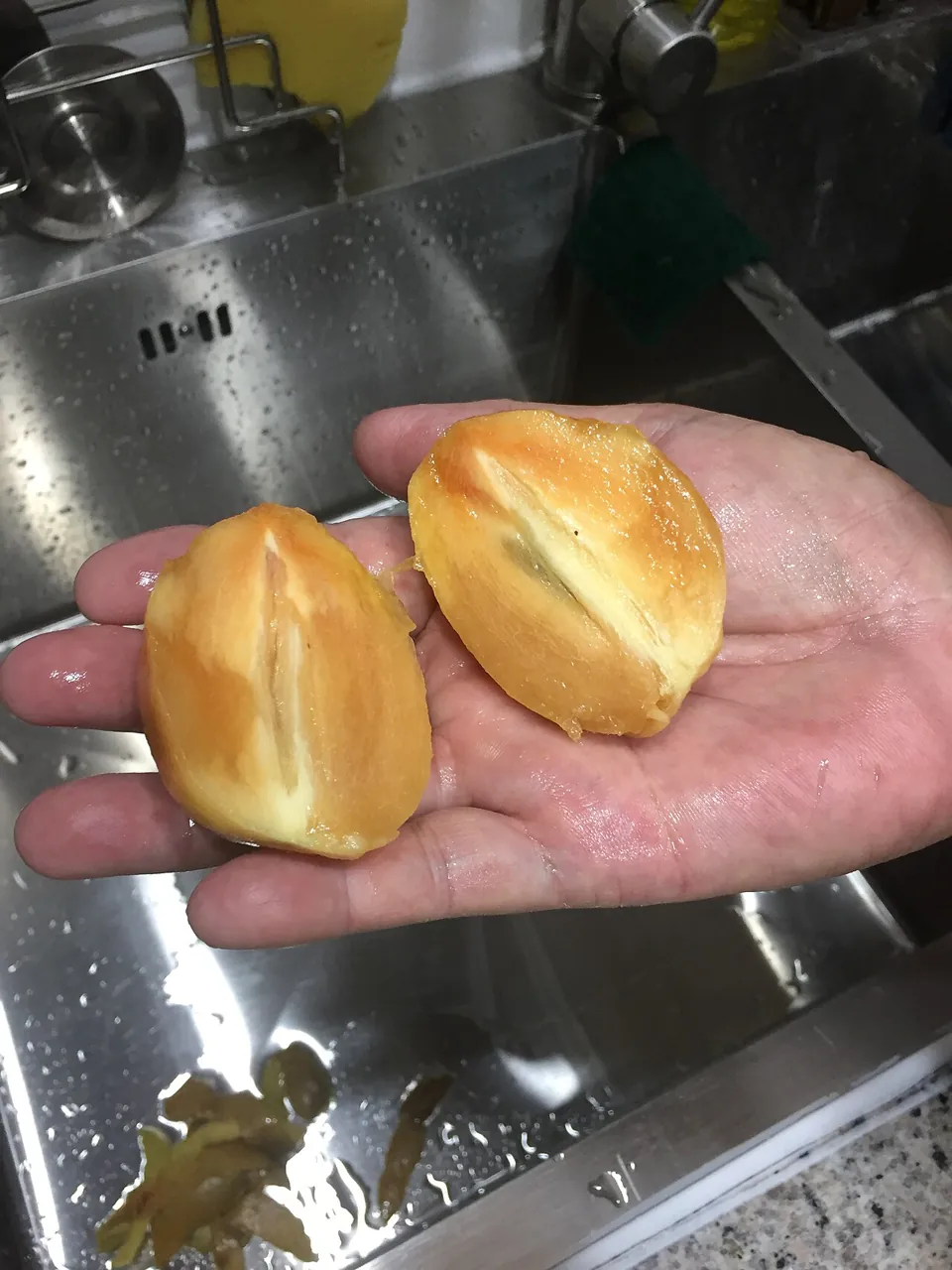 Chiku — A hand holding a chiku cut in half.