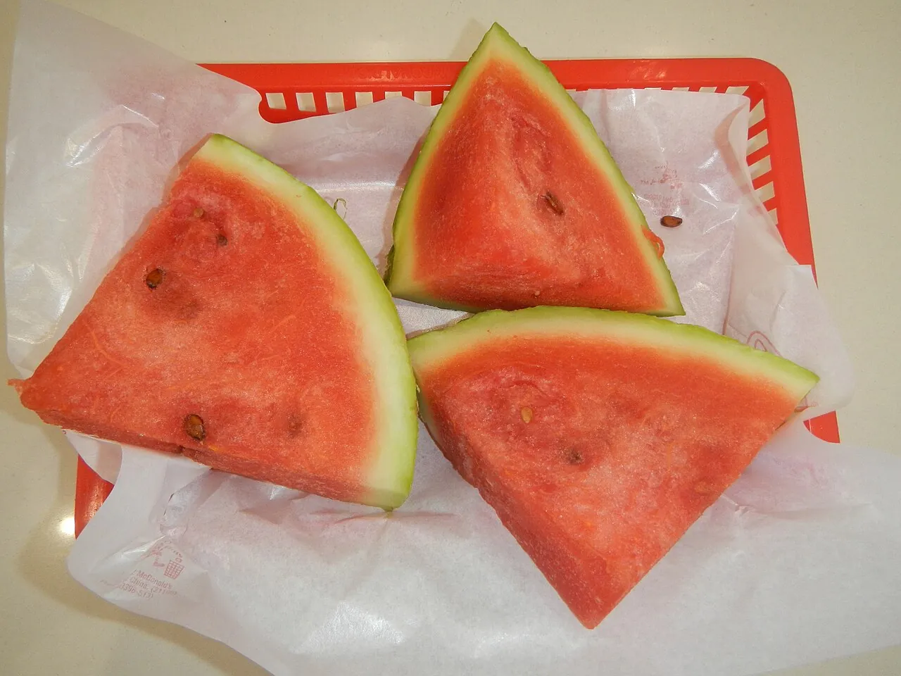 Watermelon — Triangles of watermelon on a tray, red with black seeds.