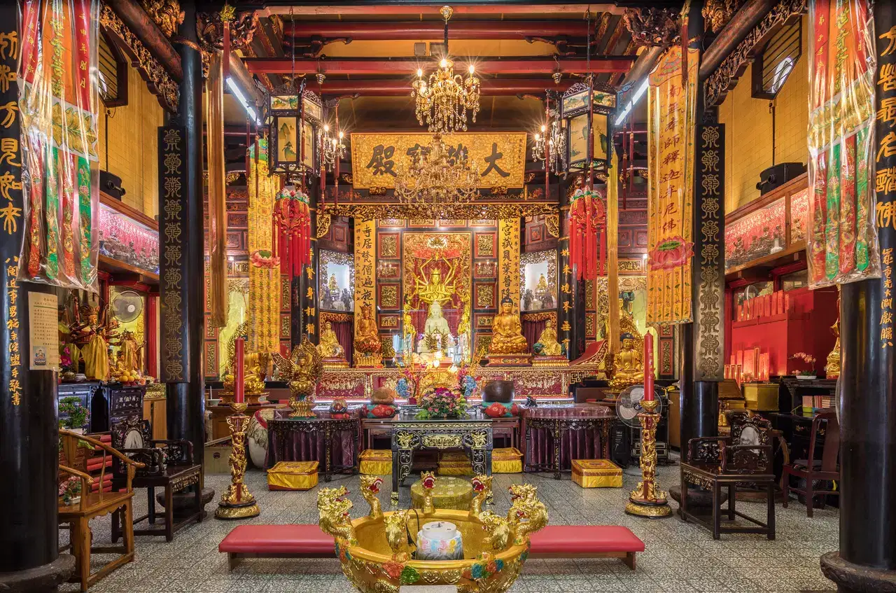 Red lanterns hang over a gold-and-red temple altar.