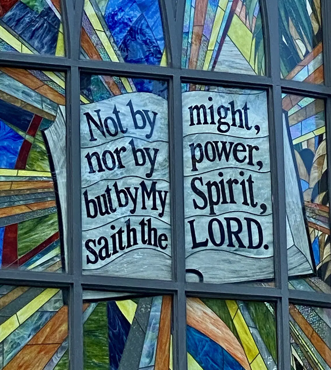 Stained-glass panels show words from a Christian prayer.