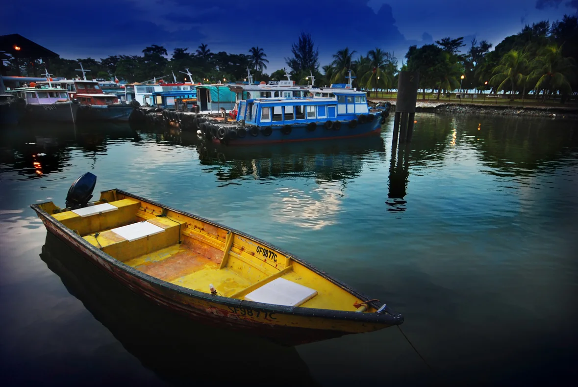 A yellow small boat and other vessels moored at Changi Point Ferry Terminal at dusk.