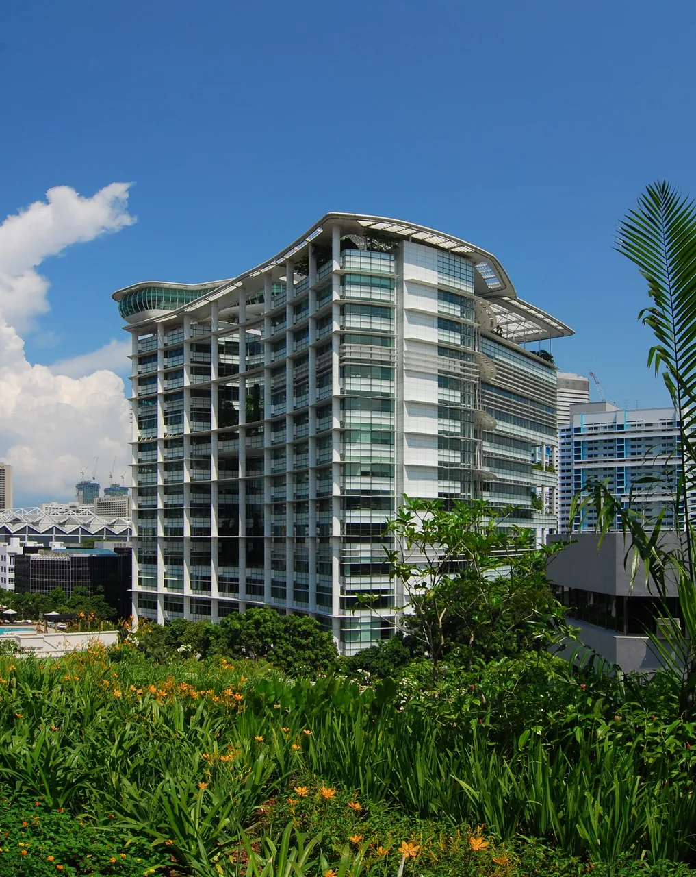 The National Library building rises above green plants under a blue sky.