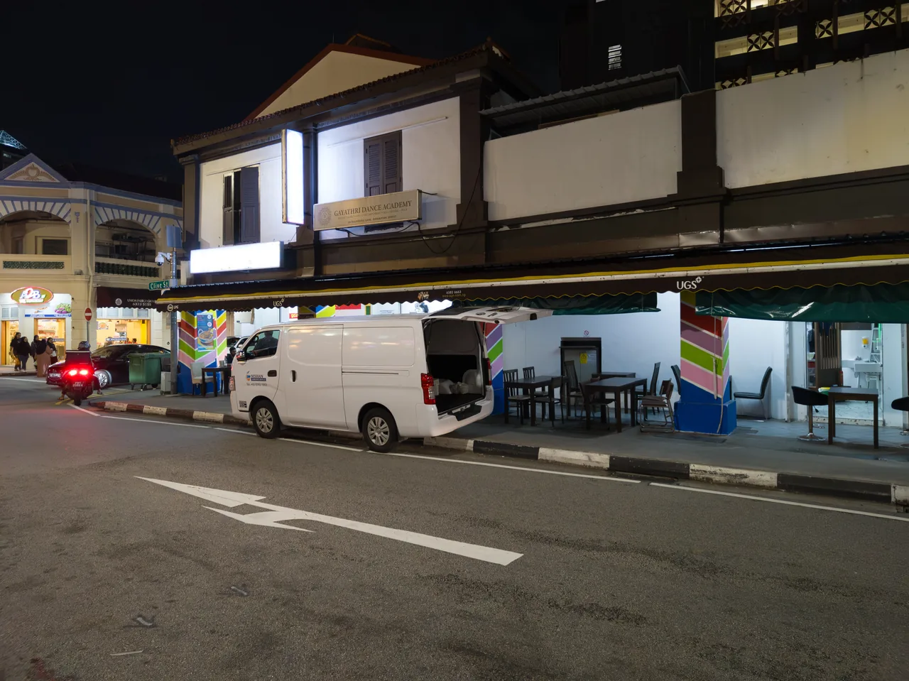 A row of Little India shophouses is lit at night, with a white van parked by the road.