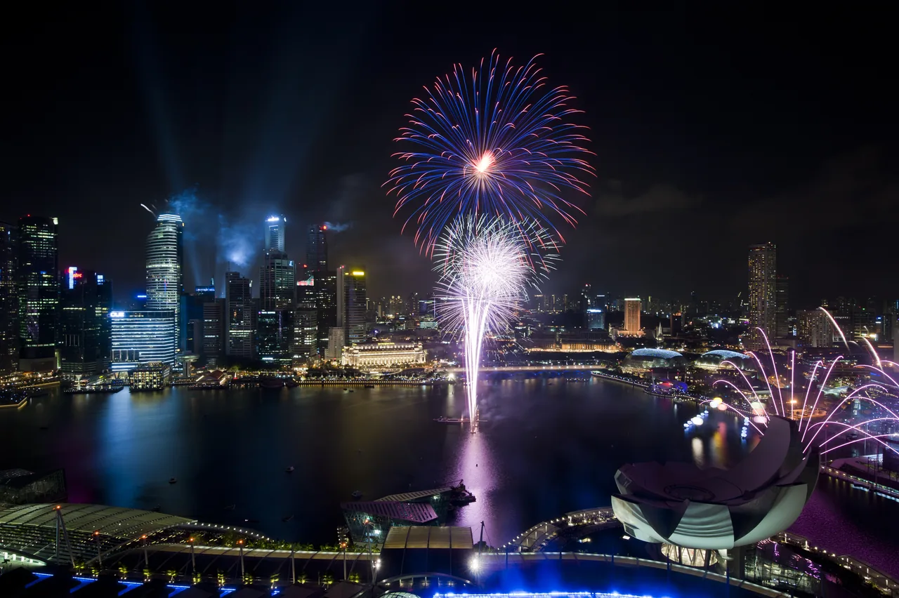 Fireworks burst over the Marina Bay skyline and water.