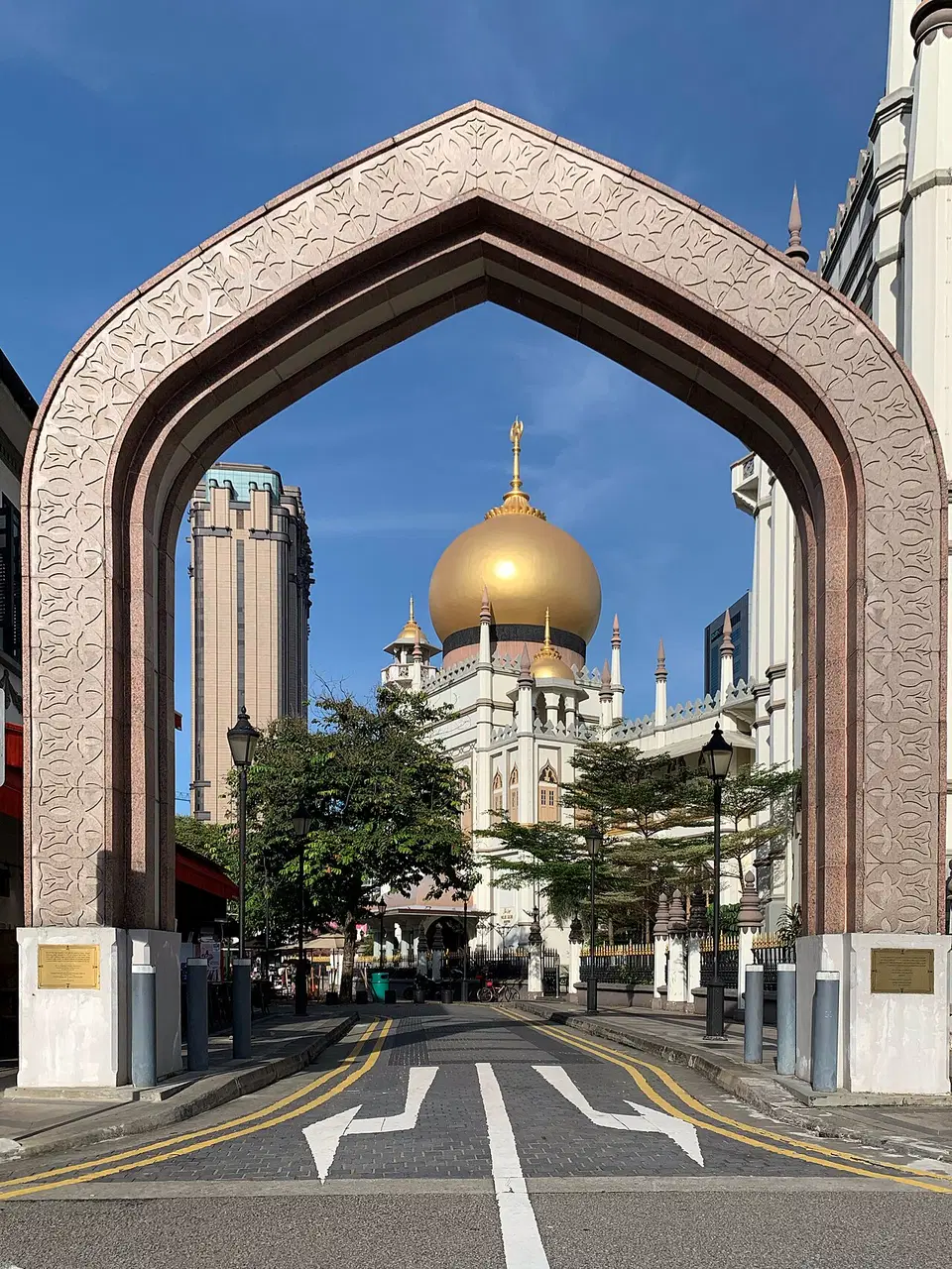 The golden dome of Sultan Mosque is framed by an arched gateway.