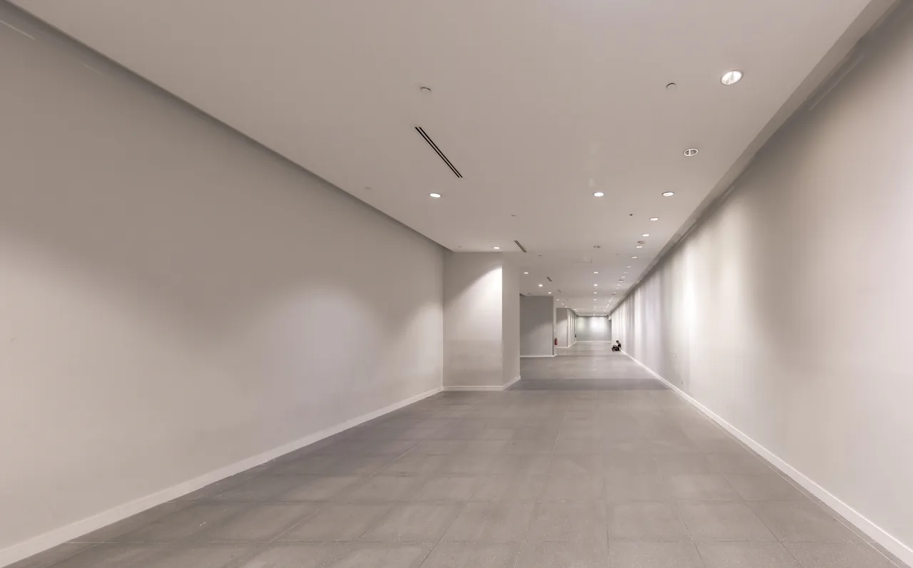 A long, clean station corridor leads to a small figure in the distance.