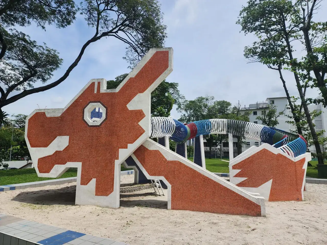 A red dragon-shaped playground structure stands under big trees.