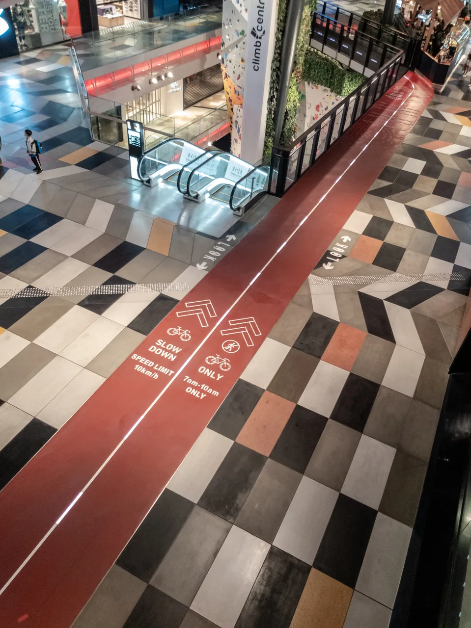 A mall interior has black-and-white floor tiles and red lines.
