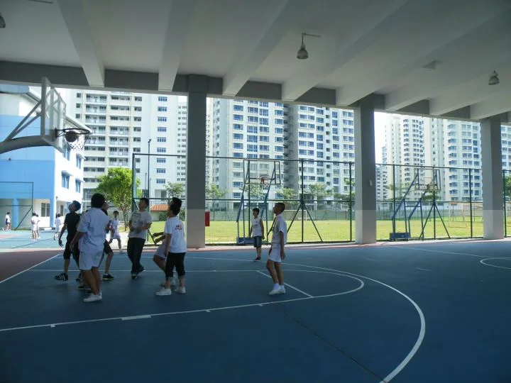 Children play basketball in an indoor Singapore sports hall.