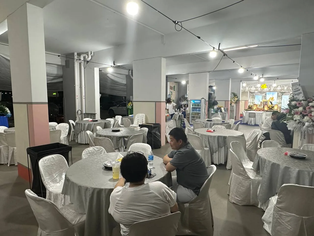 People sit at round tables in an open HDB void deck.