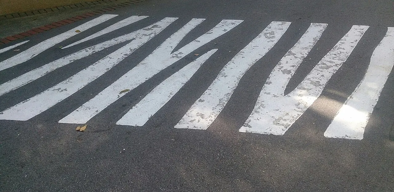 White zebra crossing stripes painted on an asphalt road surface.