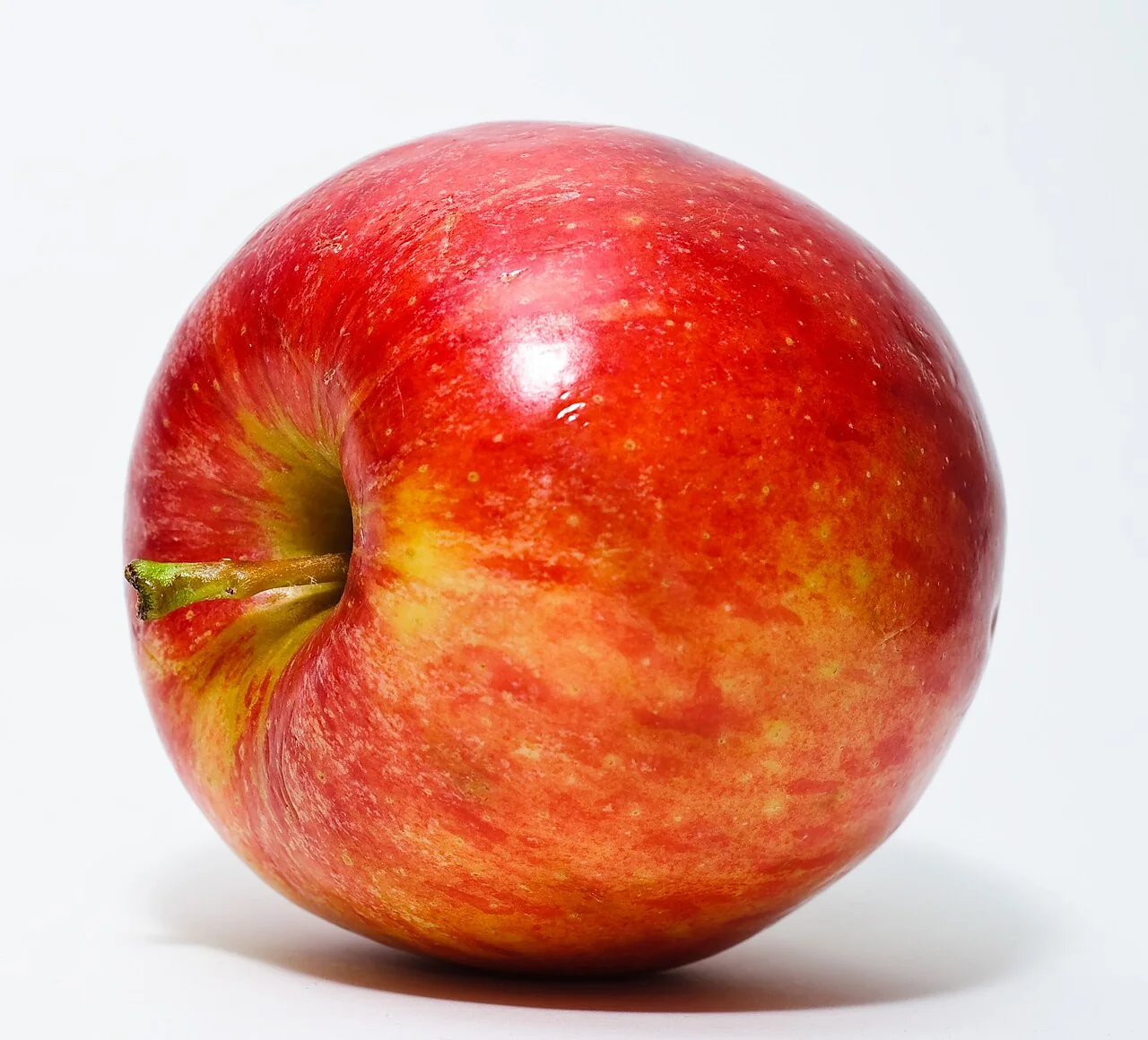 A red apple rests on a white surface.