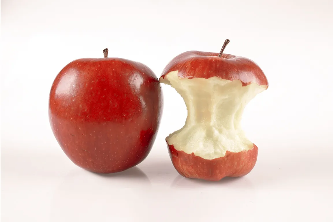 A red apple sits beside an apple core.