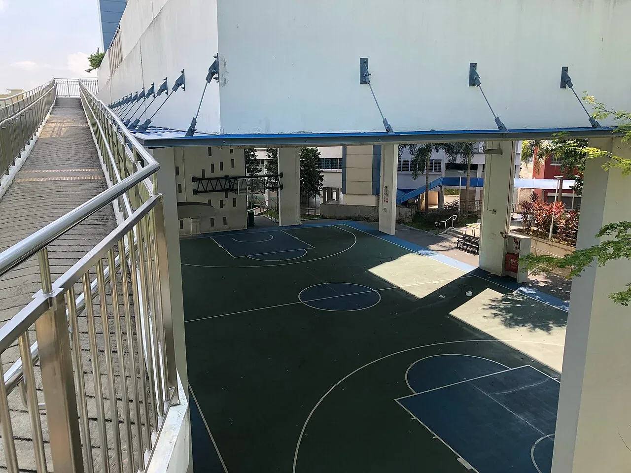 A covered public basketball court with green flooring and white markings.