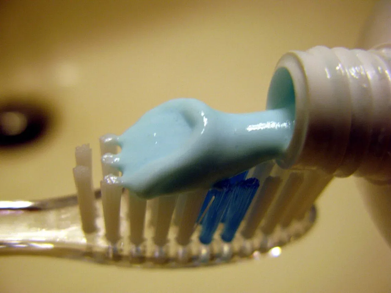 Toothpaste being squeezed onto the bristles of a toothbrush.