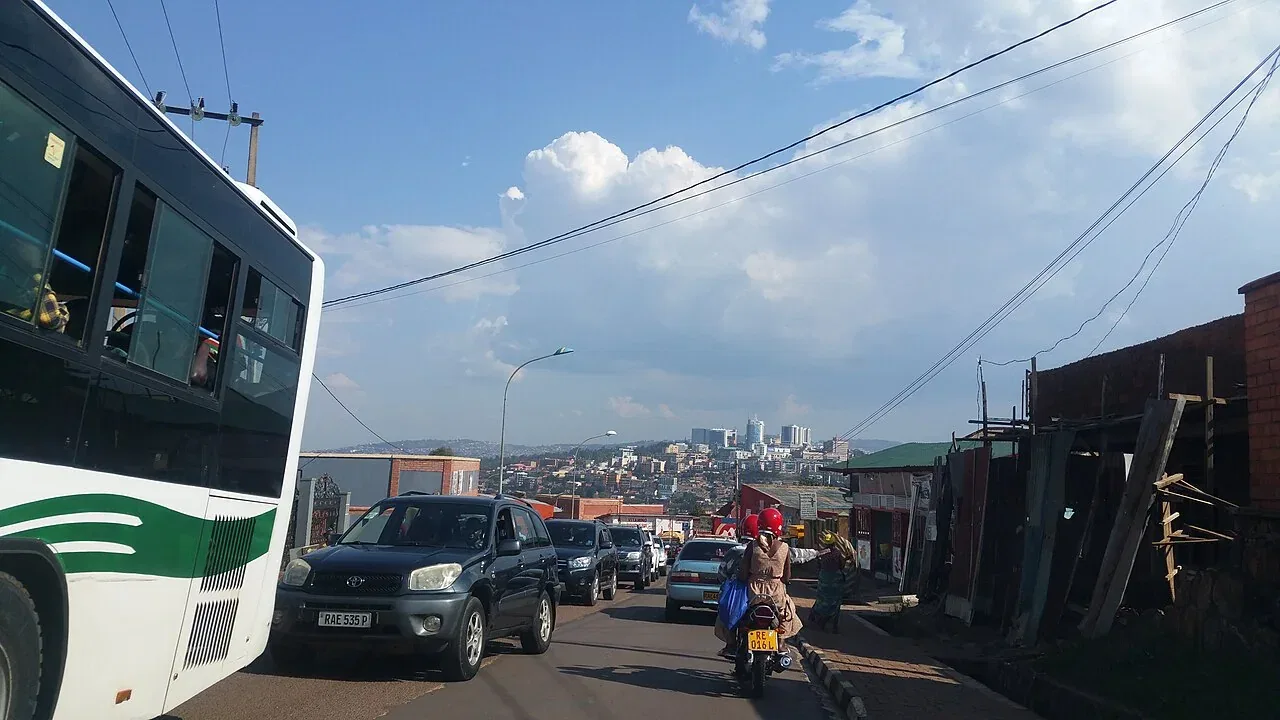 Traffic on a busy road with a bus, cars, and a motorcycle in Kigali.