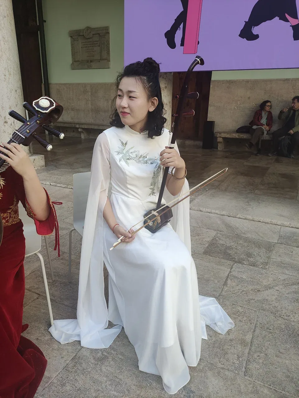 A musician in a white dress plays an erhu.