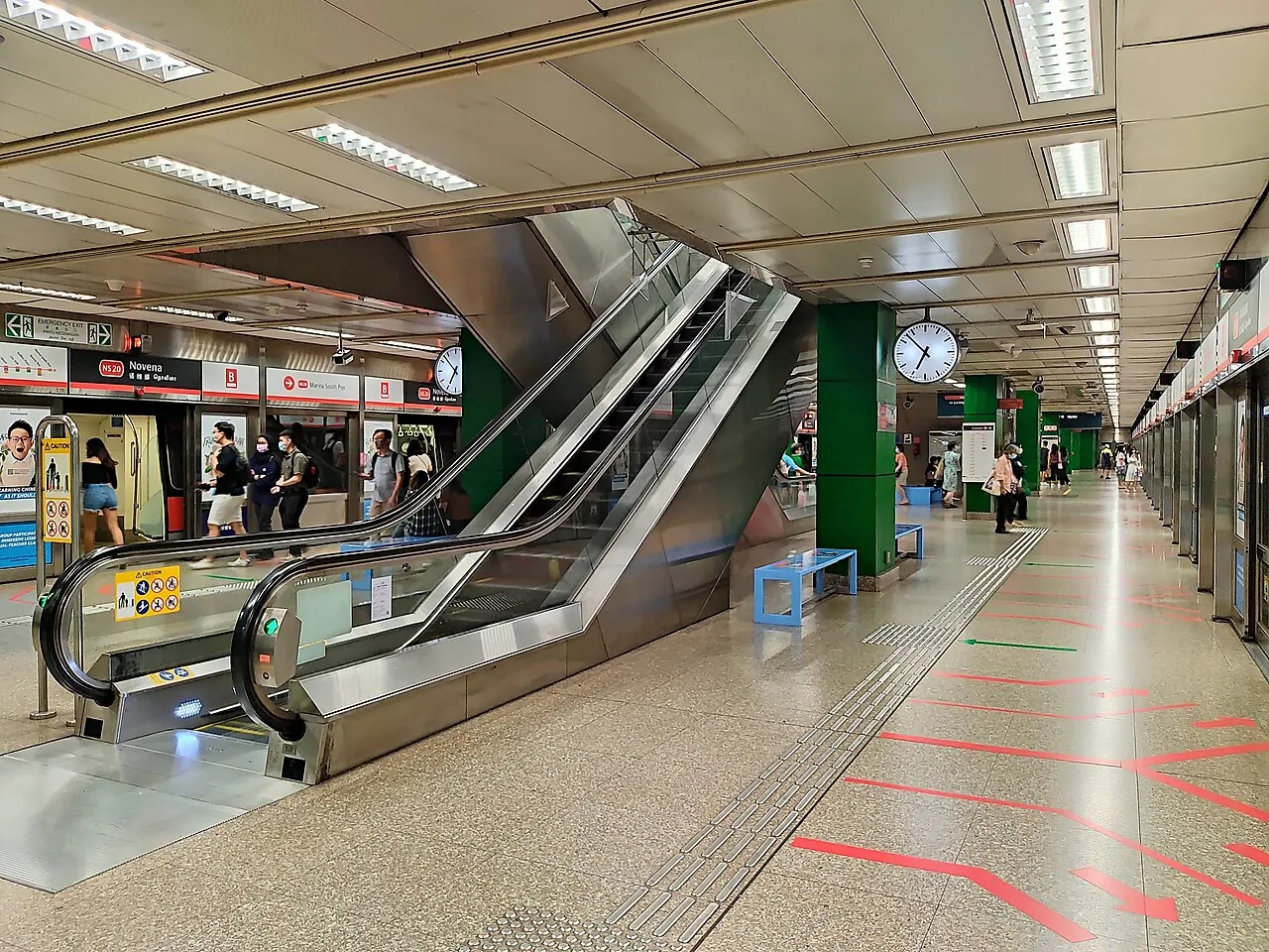 An escalator rises in a station concourse.
