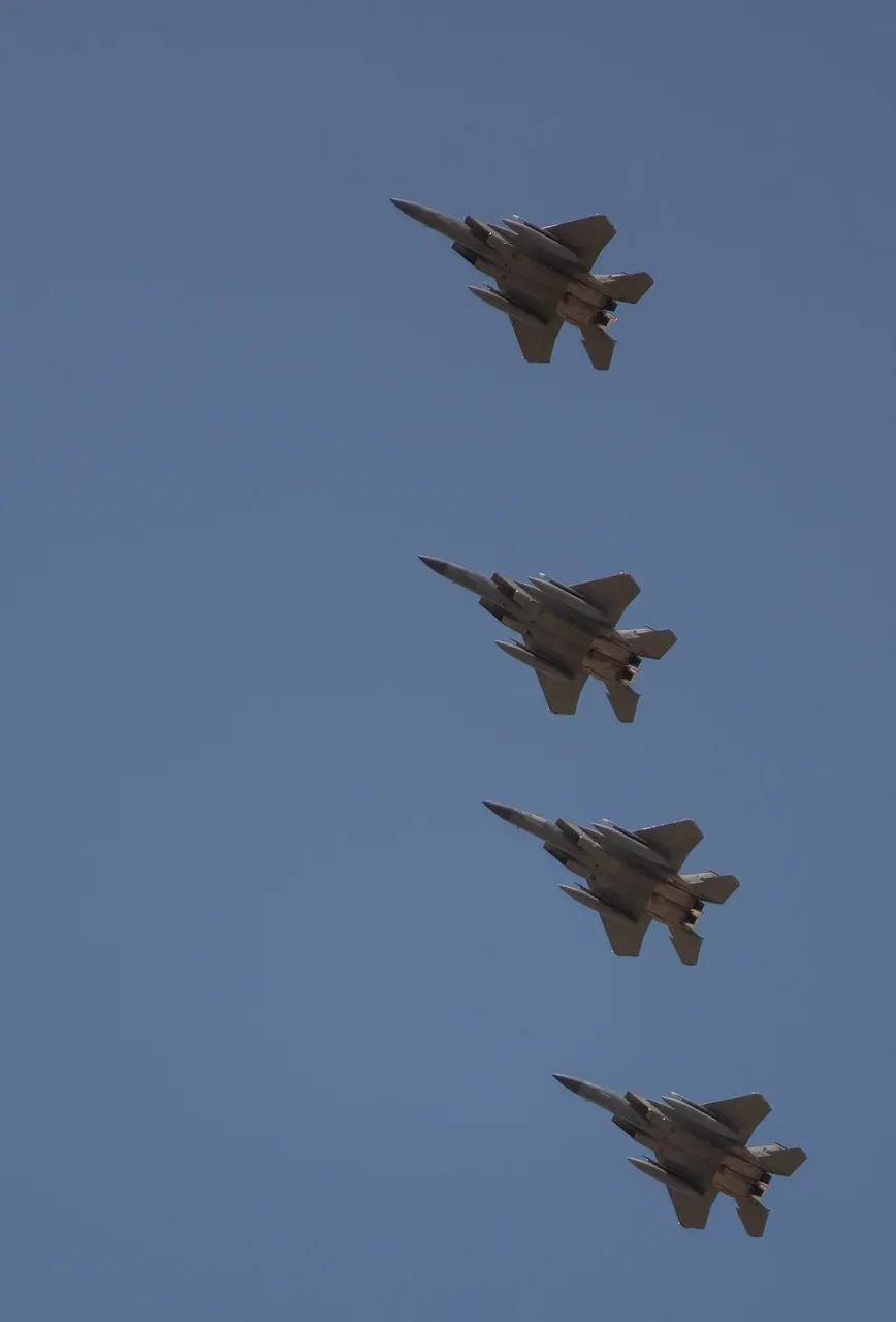 Four F-15 fighter jets flying in formation against a clear blue sky.