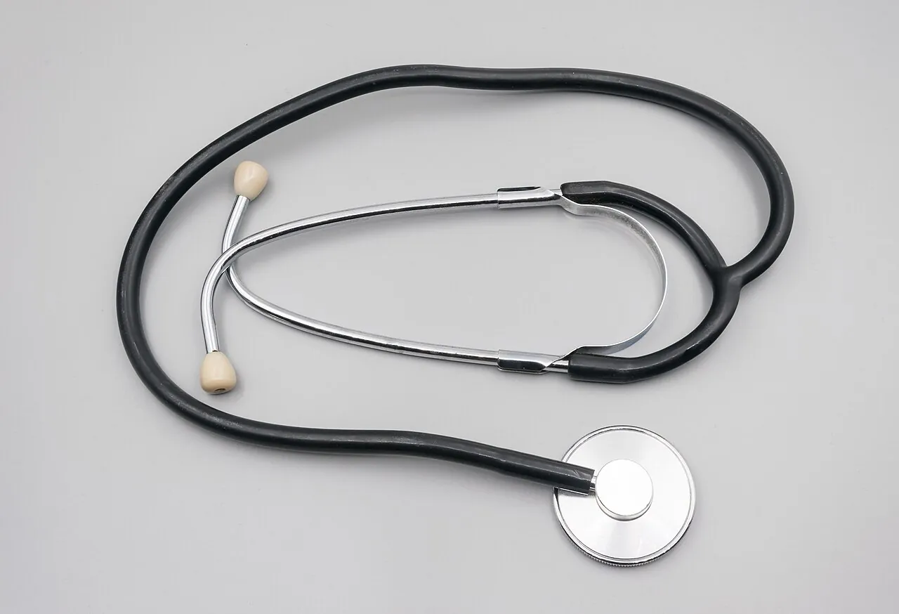 A stethoscope lies on a pale surface.