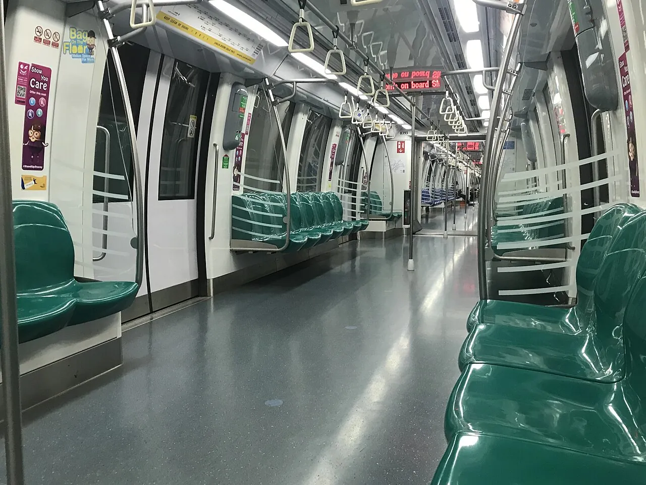 An empty train carriage has rows of green seats.