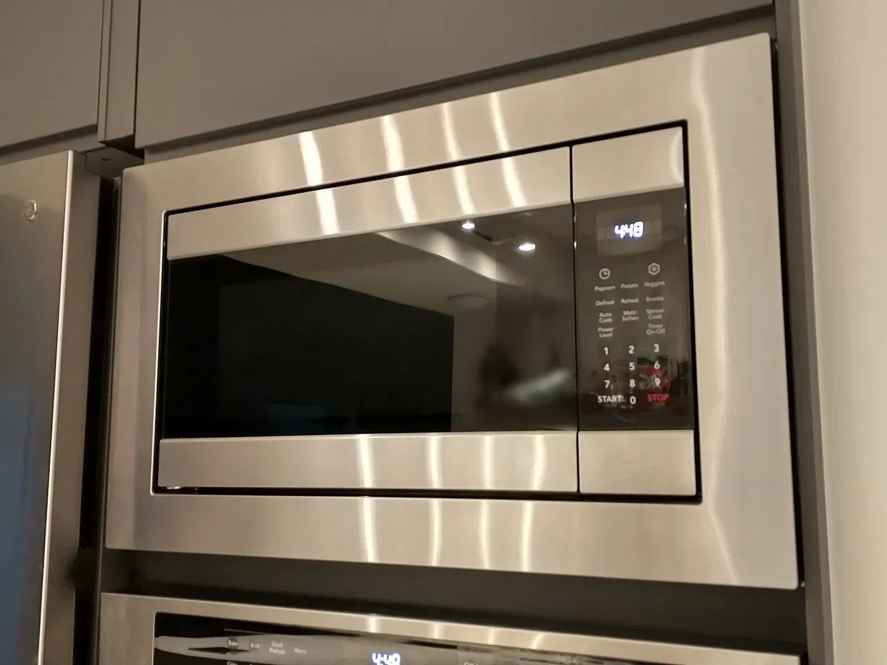 A stainless steel microwave oven with a digital display is built into kitchen cabinetry.