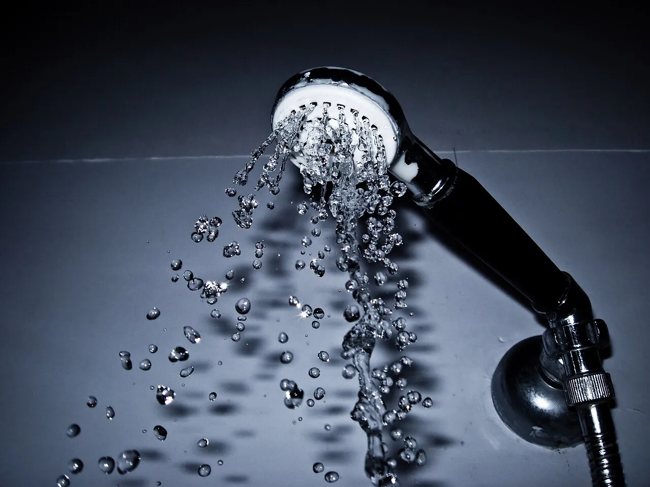 Water sprays from a handheld shower head.