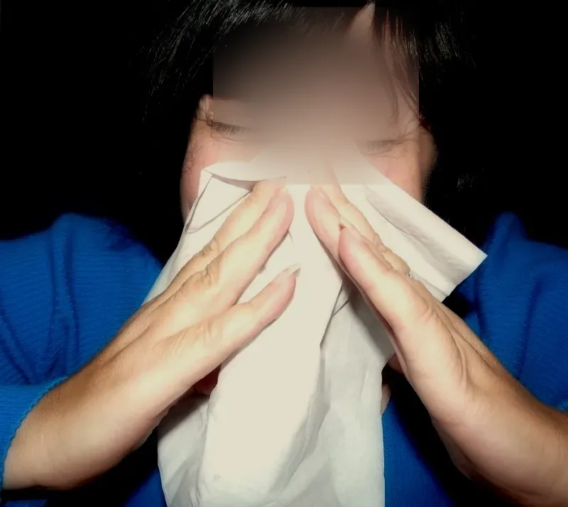A person holds a tissue over their nose.
