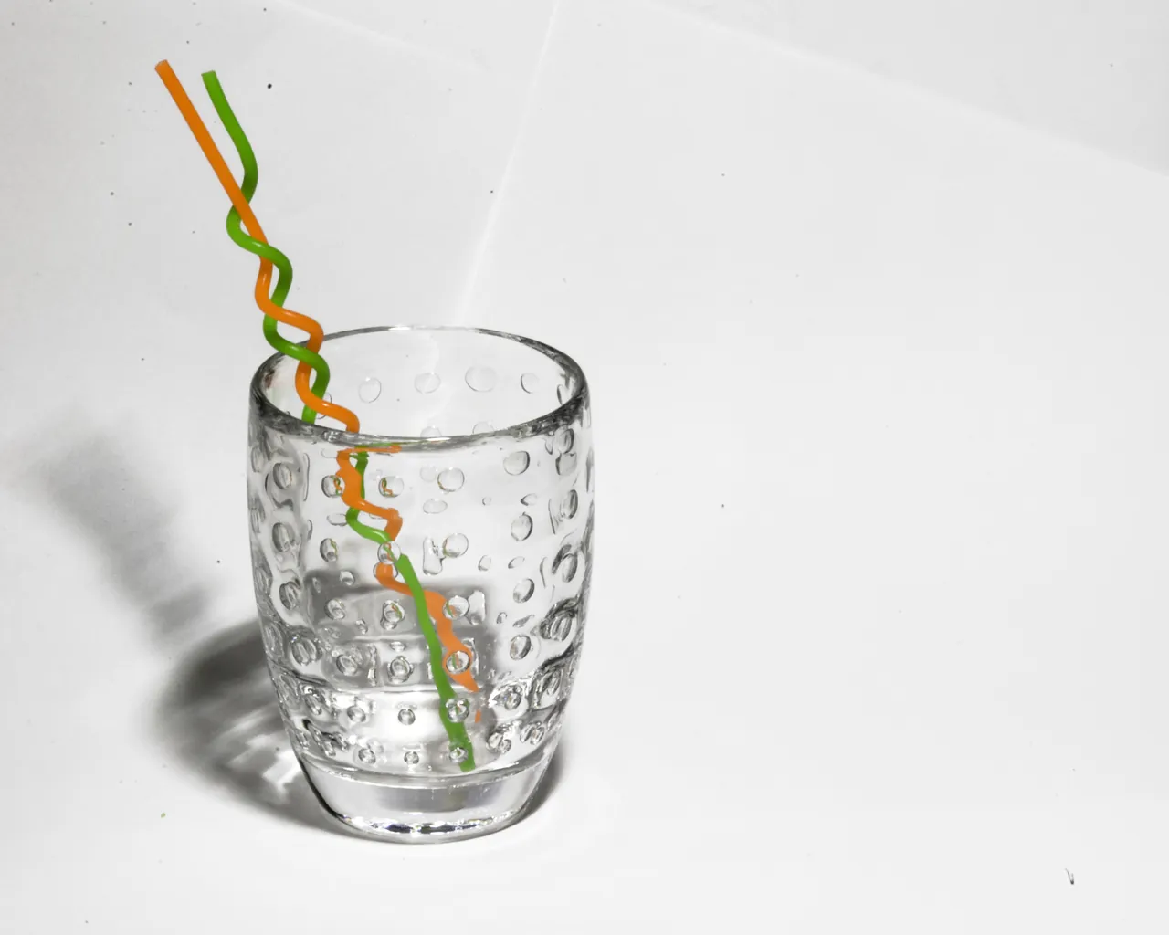 Two bent straws stand in a clear drinking glass.