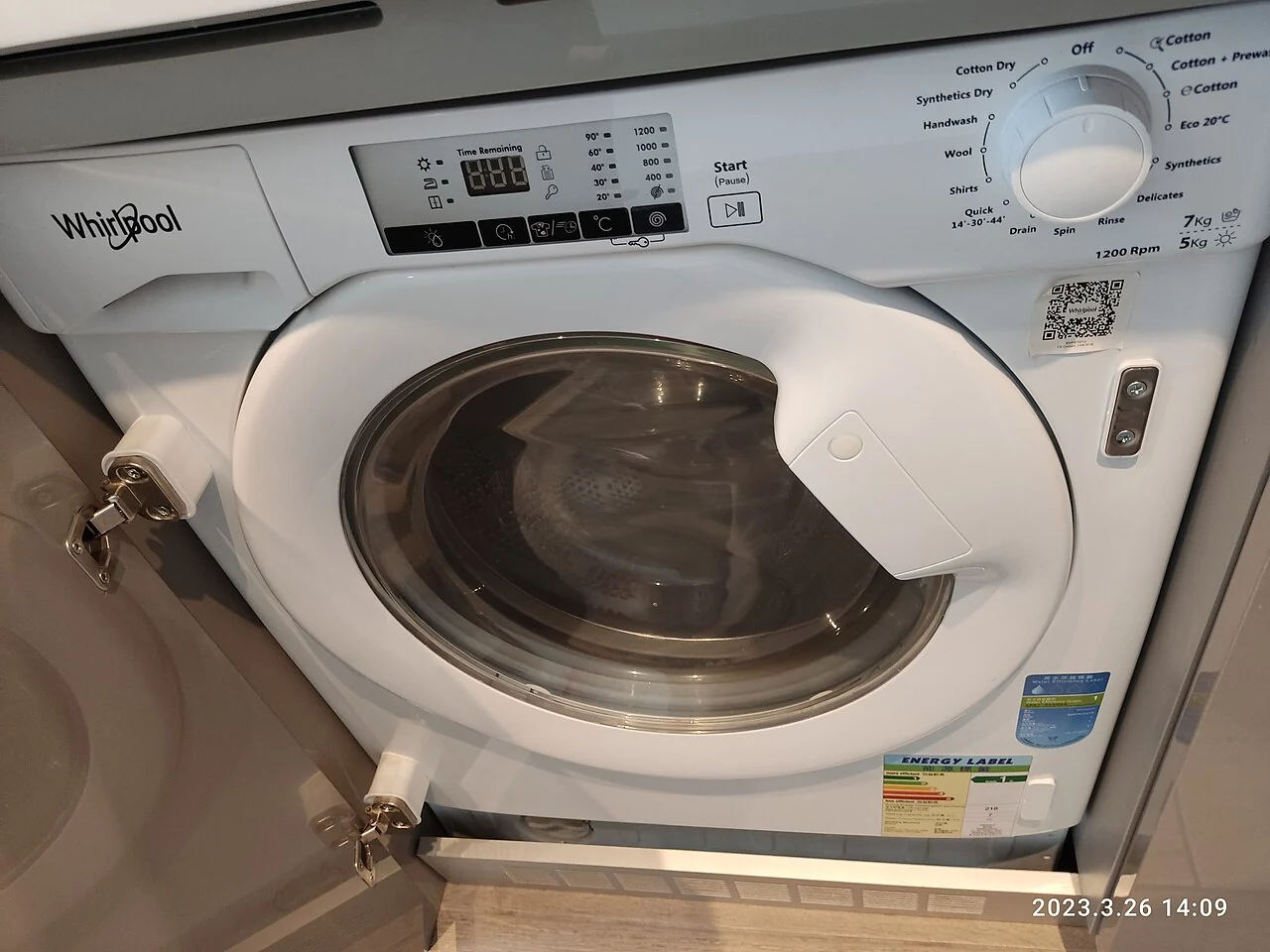 A white washing machine has a round front door and a control dial.