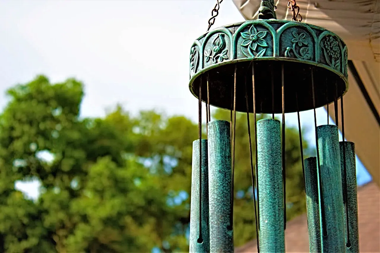 A green wind chime hangs outdoors.