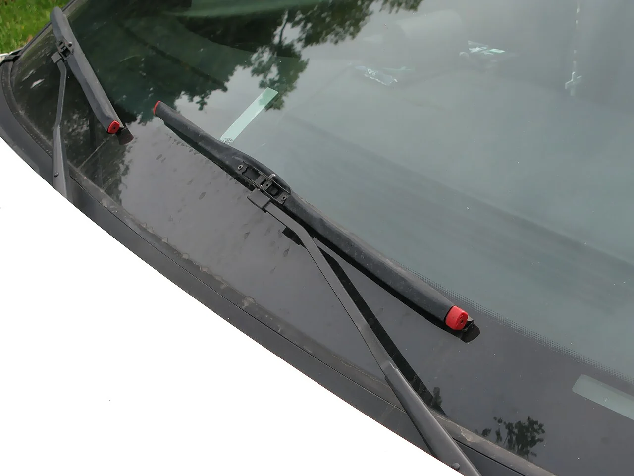 Two black wipers rest across a car windscreen.