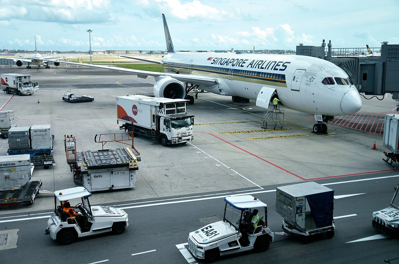 Two small white baggage tractors have open sides and flat roofs in the foreground.