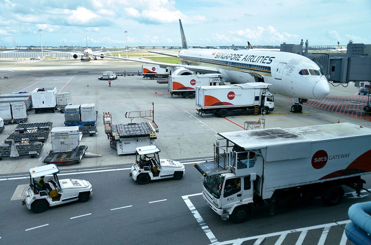 A white cargo loader near the centre has a flat roller platform and orange guard rails.